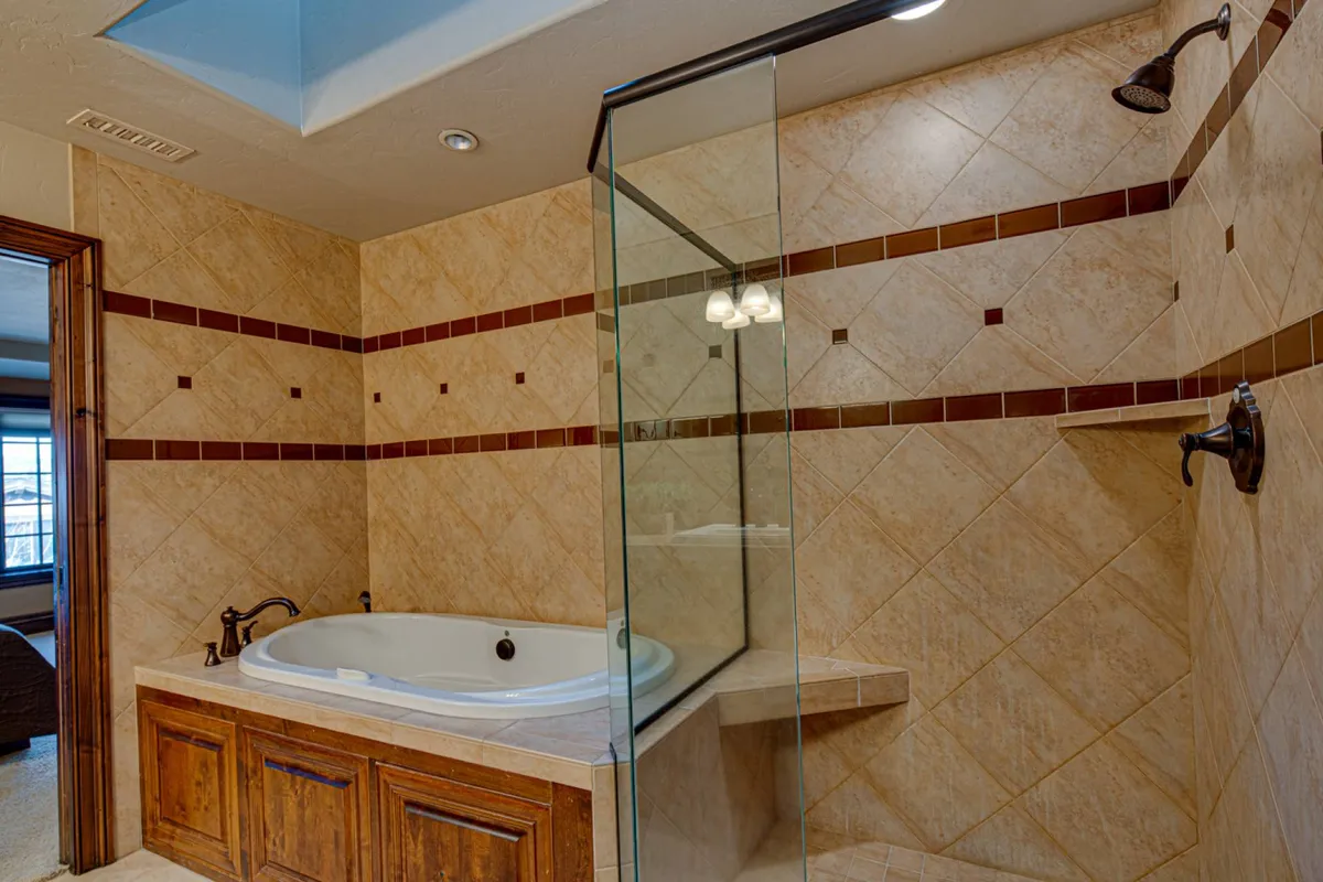 A luxurious bathroom featuring a freestanding bathtub, a glass-enclosed walk-in shower, and textured tile walls. The space is tranquil and designed for self-care routines or a soothing soak after a long day.