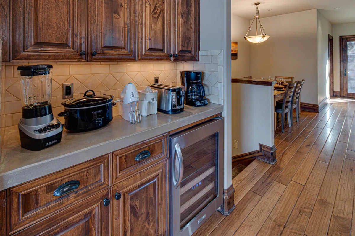 A view of the kitchen with high-end appliances, wood cabinetry, and a connected dining area. The image radiates warmth and hospitality, ideal for both intimate family moments and larger gatherings.